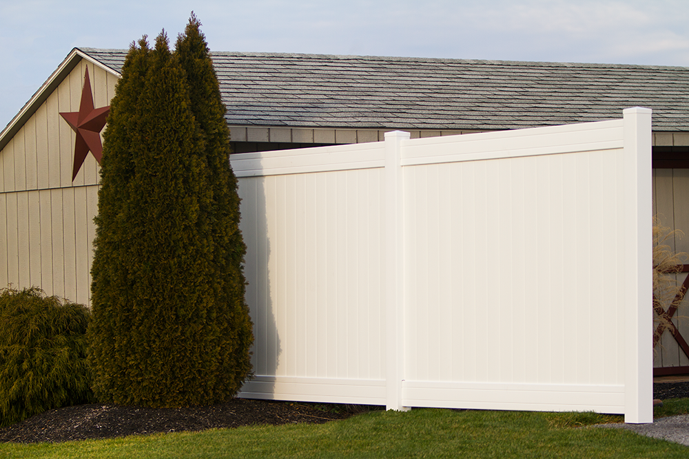 Image of a barn with a primitive star decoration, complimented by a white vinyl privacy vence.