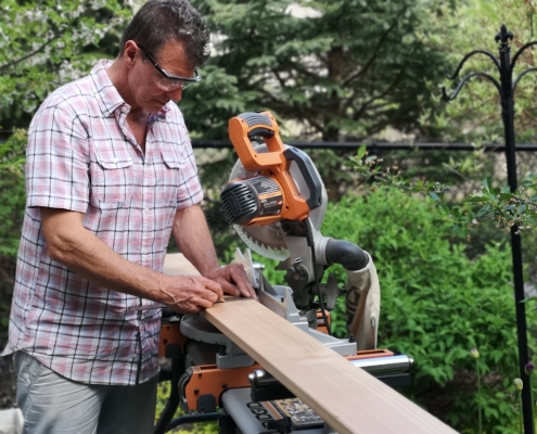 Man using miter saw to cut fence panel