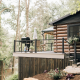 Rustic cable with composite deck with aluminum vertical cable railing overlooking wooded area and stream