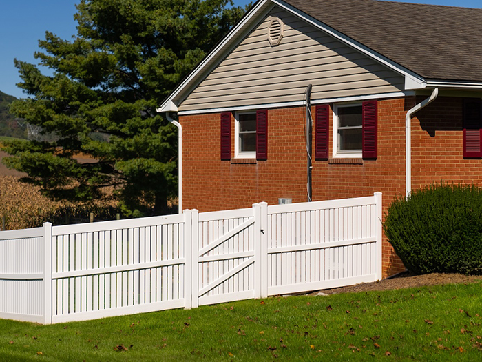 White vinyl privacy fence next to brick house
