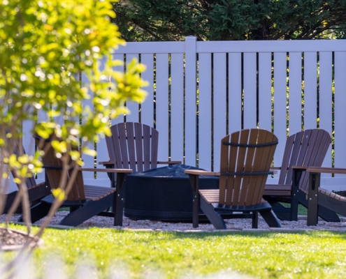 Backyard fire pit set up with white vinyl yard fence
